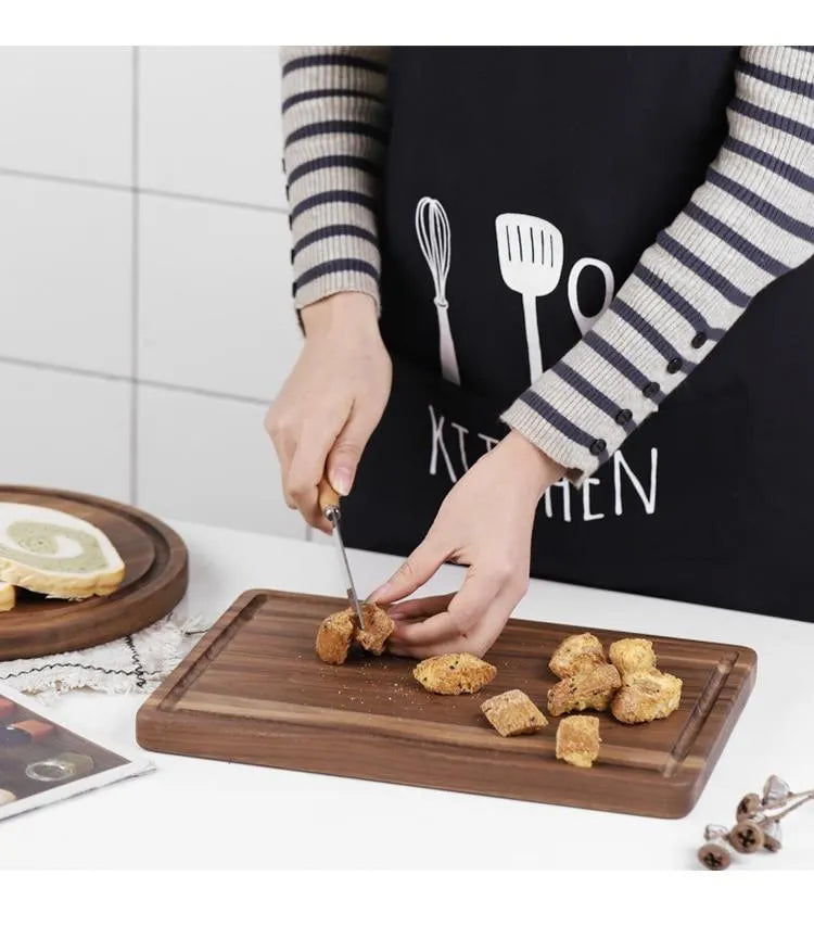 Black walnut wood double-sided cutting board with juice groove and side handle on kitchen counter