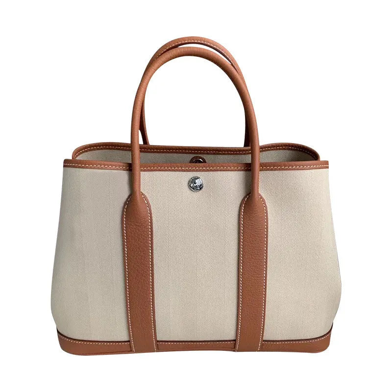 Women's canvas bucket tote bag with leather trim showing crossbody strap and internal compartments