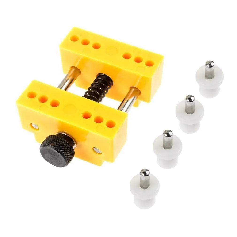 Yellow plastic watch repair case opener kit with mounting base and four fixing pillars on a workbench