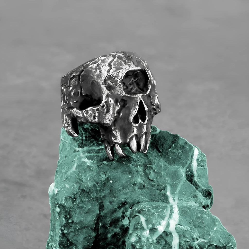 Close-up of a silver-toned alloy ring featuring a detailed one-eyed skull design on a finger.