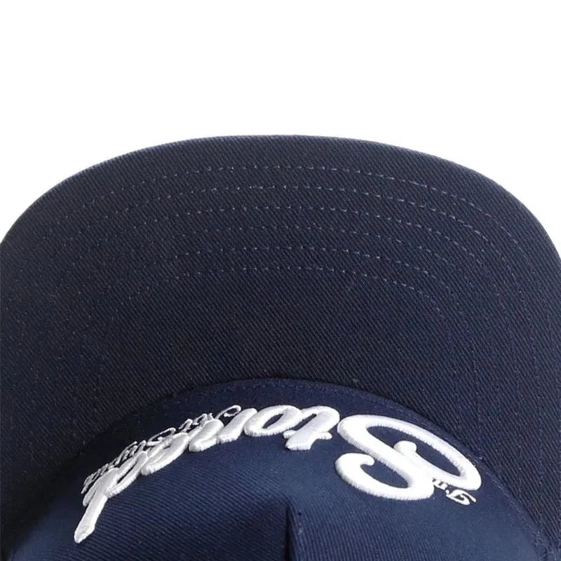 Navy blue cotton baseball cap with machine-embroidered English letters on front, dome crown, adjustable back strap