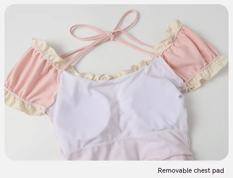 Pink women's conservative one-piece swimsuit with Siamese-style detailing on mannequin