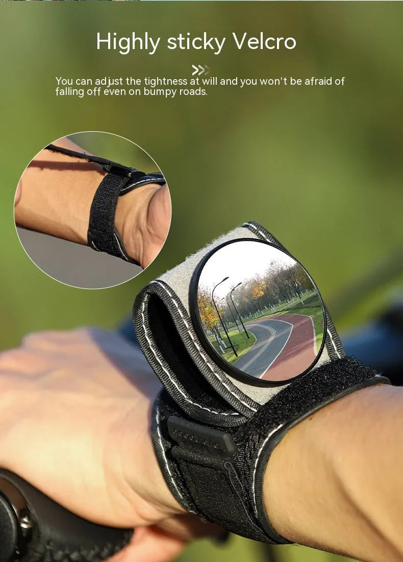 Black nylon wrist-mounted bicycle rear-view mirror shown on a cyclist's wrist.