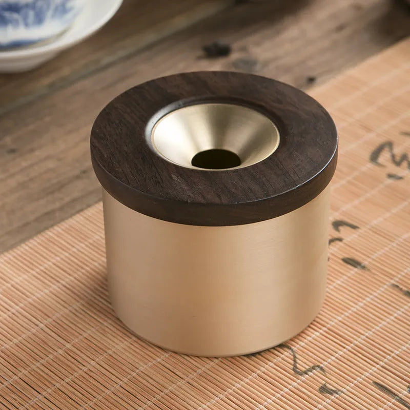 Brass ashtray with wooden lid showing central aperture design