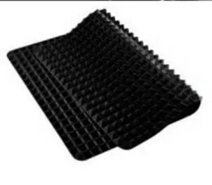 Red non-stick silicone pyramid cooking mat with grid on a baking tray for oven or BBQ use