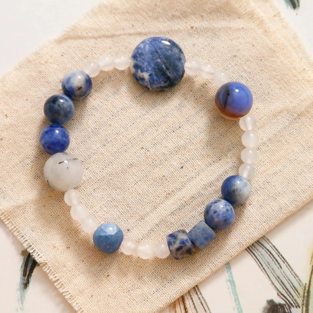 Natural blue point stone and black hair crystal agate hand-woven unisex bracelet with round and oval beads on white background