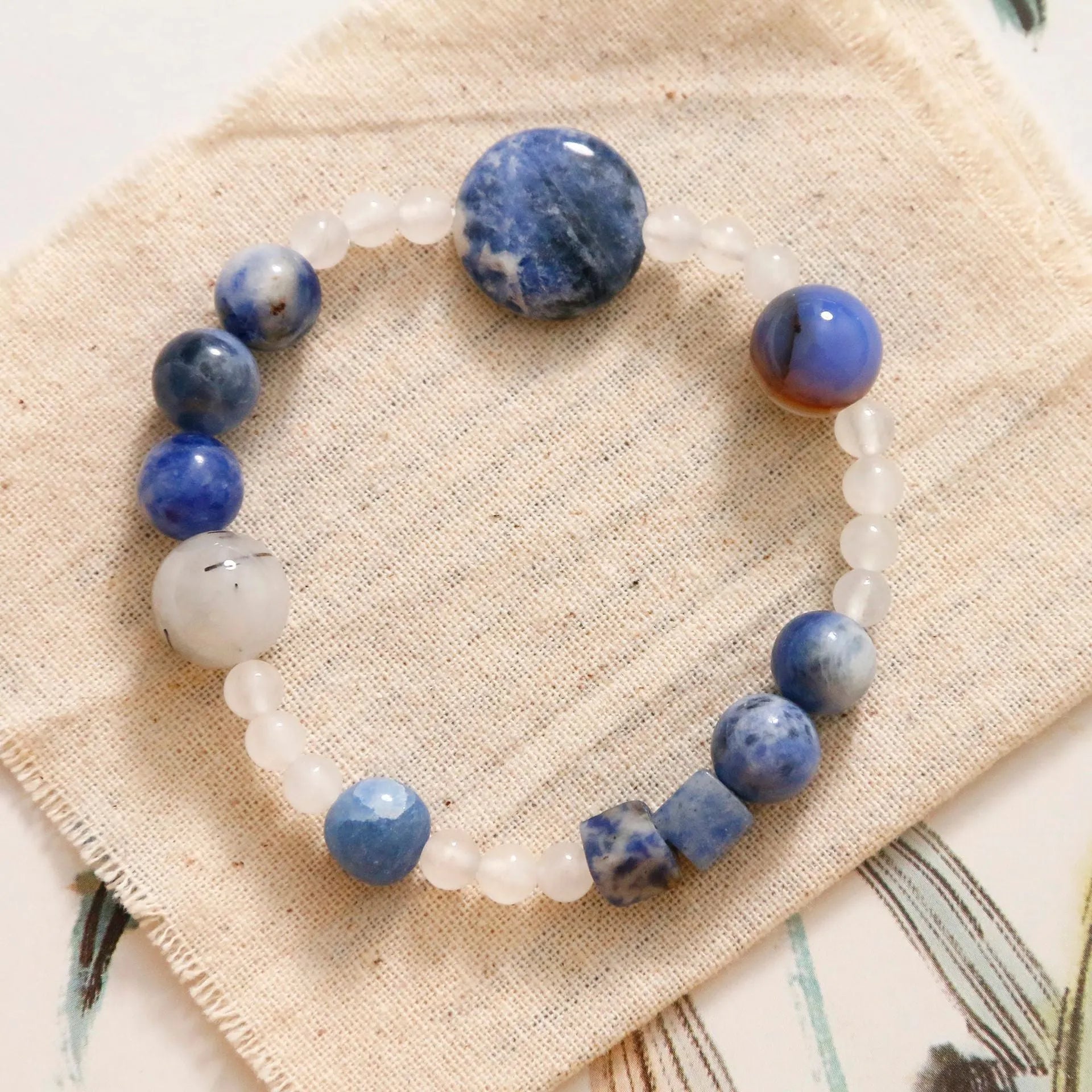 Natural blue point stone and black hair crystal agate hand-woven unisex bracelet with round and oval beads on white background