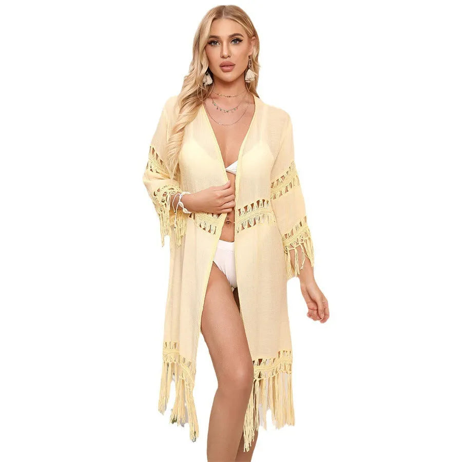 Women's yellow hand-crocheted acrylic beach cardigan with tassel detailing on a hanger.