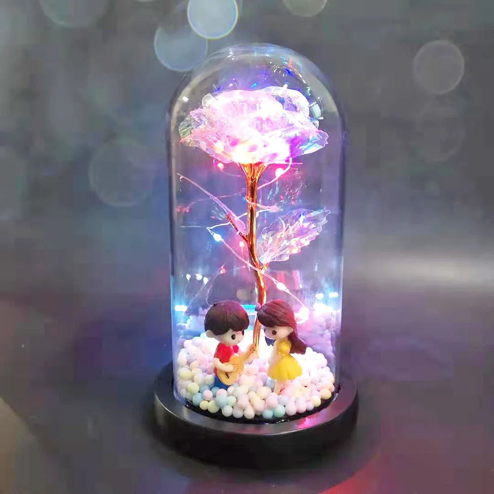 Artificial gold rose in glass flask with LED lights on black base, 20cm tall