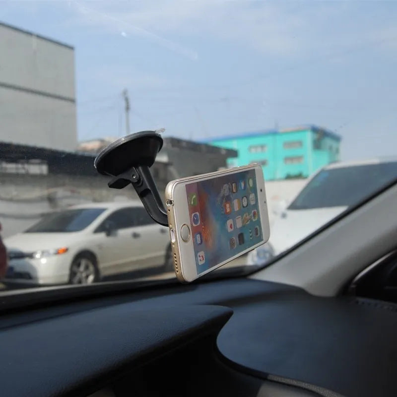 Black magnetic car phone holder with strong magnet mounted on dashboard, holding a smartphone in landscape mode