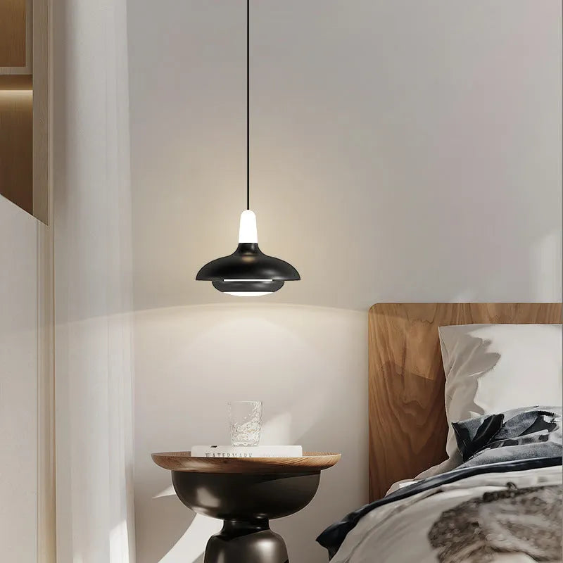 Modern minimalist adjustable bedside pendant light in Moon White shown over a small bedside table