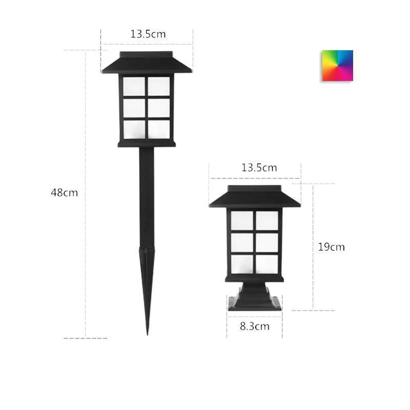 Solar outdoor LED lawn light with black body and white light through windows, set in a garden flower bed