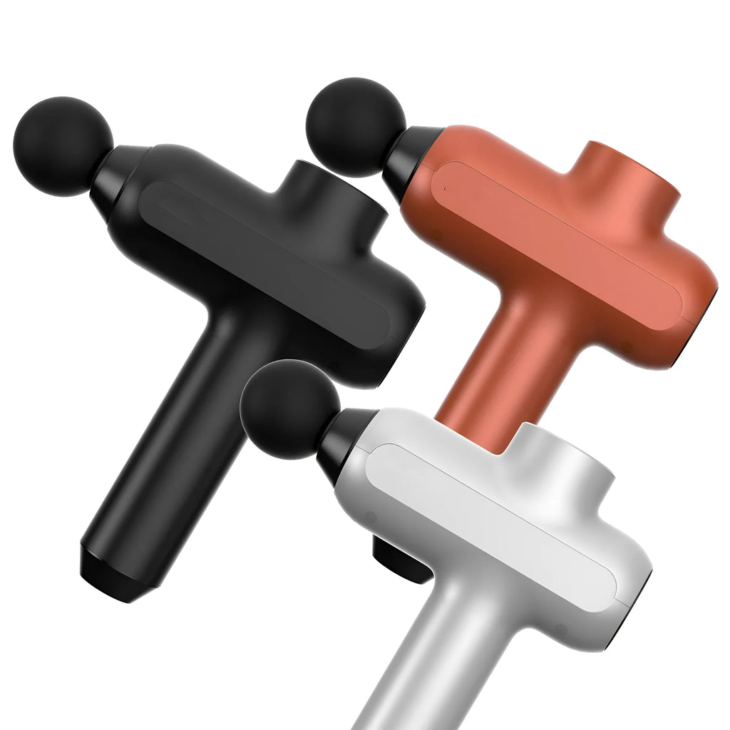 Handheld black muscle percussion massager with six different coloured attachment heads on a table.