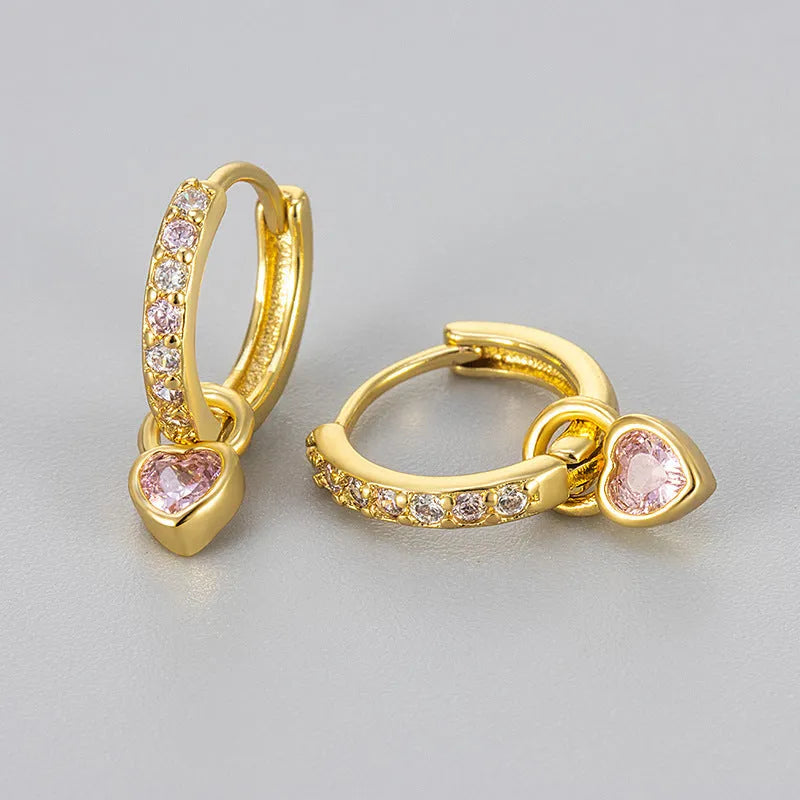 Women's heart-shaped clip-on earring with coloured gemstone centre on a gold-coloured metal setting.