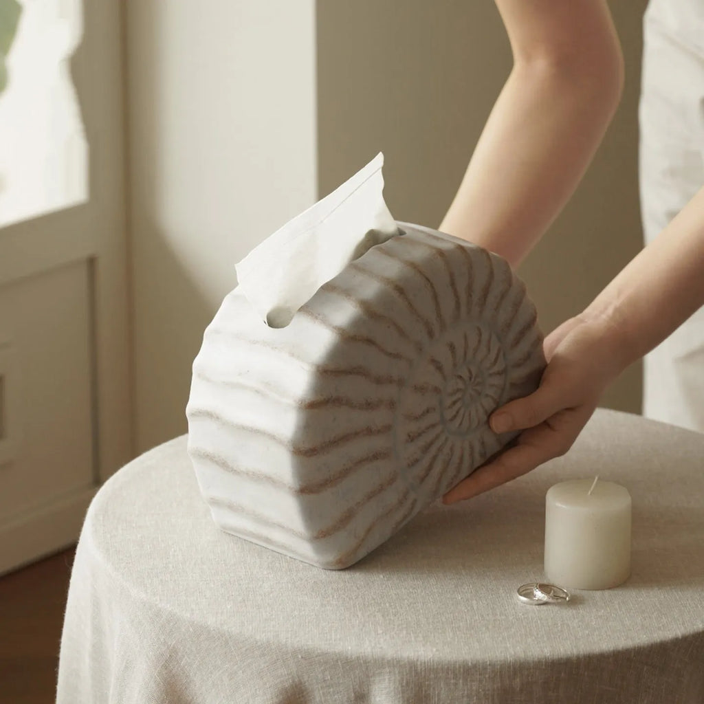 White conch shell shaped resin cover for a rectangular tissue box with a slot for tissue dispensing.