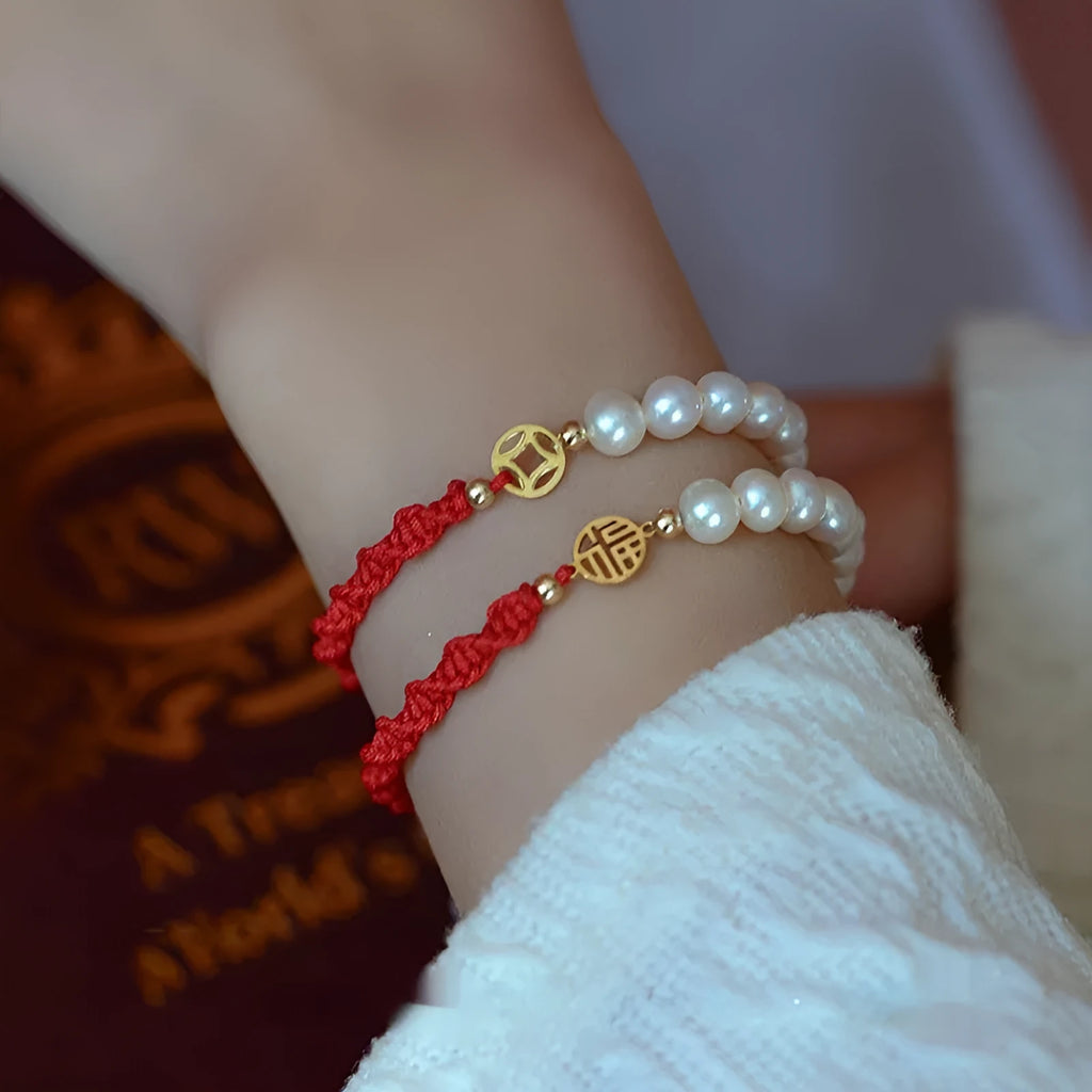 Women's pearl braided red rope bracelet with 14K gold plated fu character charm in geometric shape on white background
