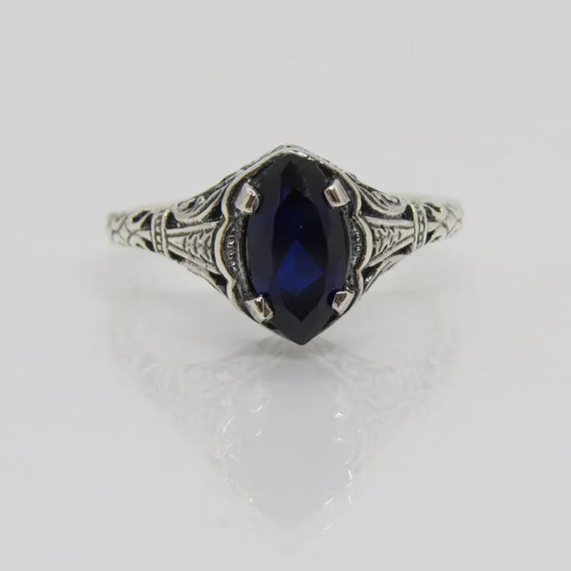 Women's silver alloy ring with geometric hollow design and central zircon stone, on a plain background