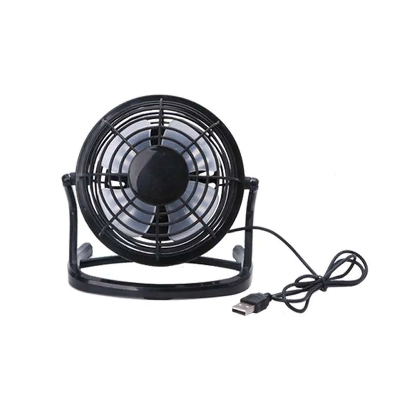 Small black USB desk fan with adjustable head on a wooden desk next to a laptop