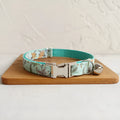 Green adjustable pet collar made of cloth and webbing on a neutral background