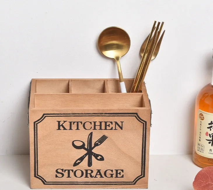 Open wooden kitchen storage box with internal grid holding knives, forks, and chopsticks.