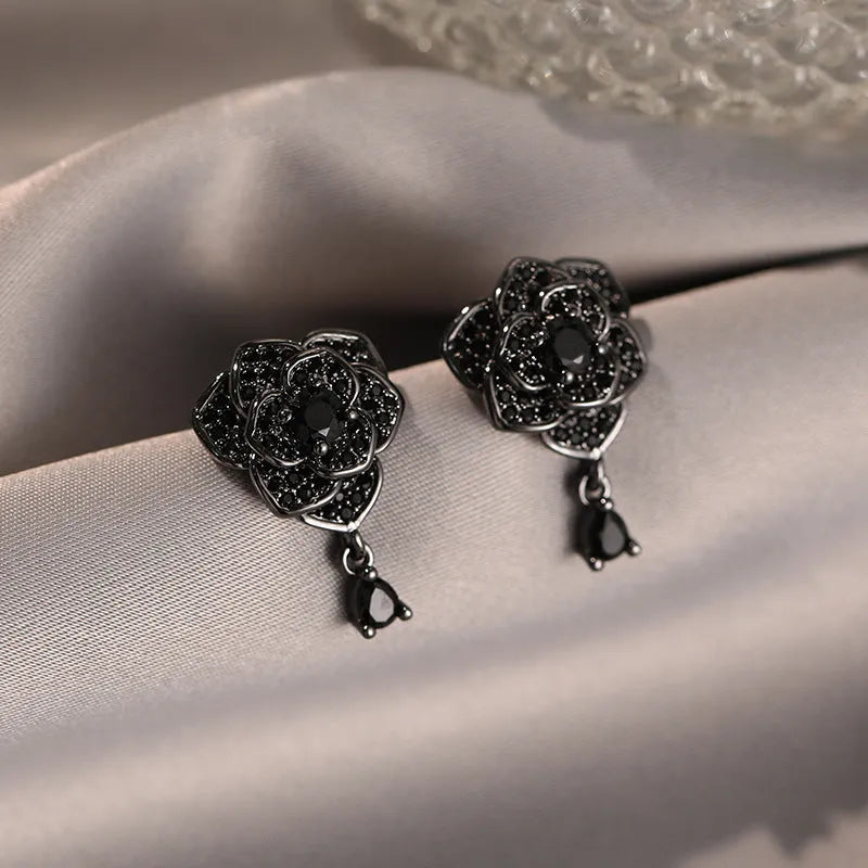 Black rose zircon inlaid stud earrings with 18K gold plated copper flower shape on white background