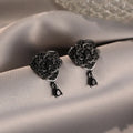 Black rose zircon inlaid stud earrings with 18K gold plated copper flower shape on white background