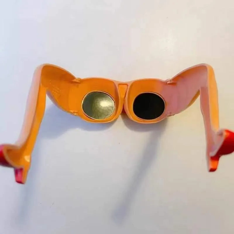 Orange plastic novelty sunglasses shaped like legs and hips on a white background.