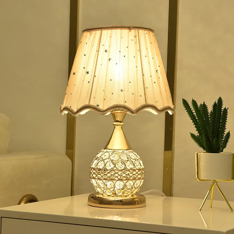 Gold crystal desk lamp with remote control and dimming switch on a bedside table