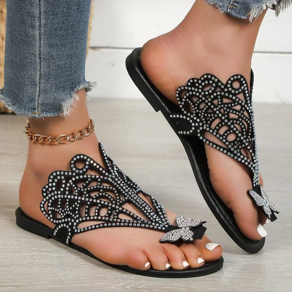 Women's black slip-on sandals with rhinestone accents and flip-toe design on flat rubber sole