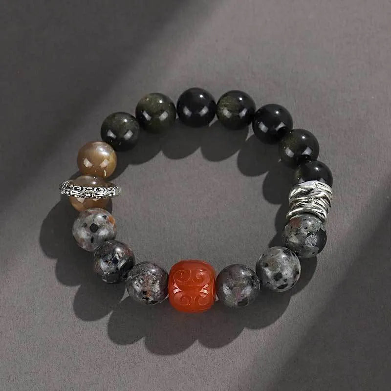 Gold obsidian flame stone and red agate unisex bracelet on a neutral background