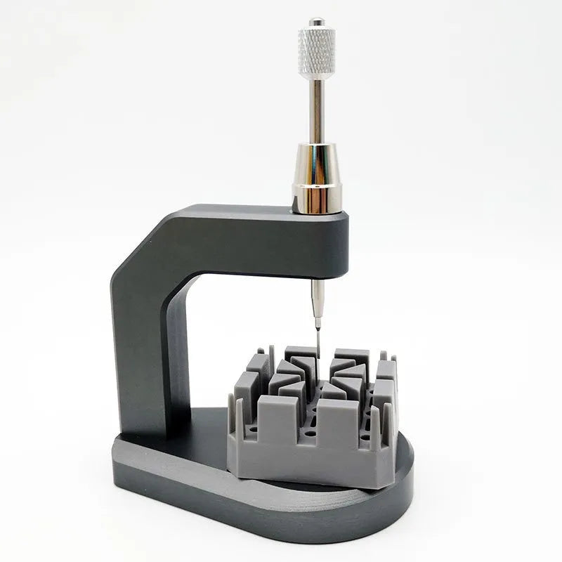 Silver multi-purpose press strap removal tool made from tool steel on a work surface.