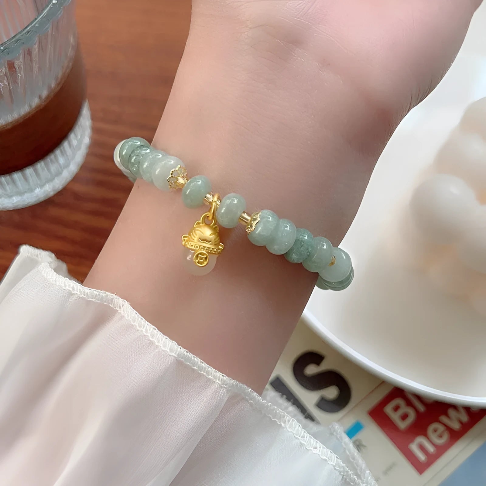 Women's handmade strawberry quartz Lucky Cat bracelet on a neutral background