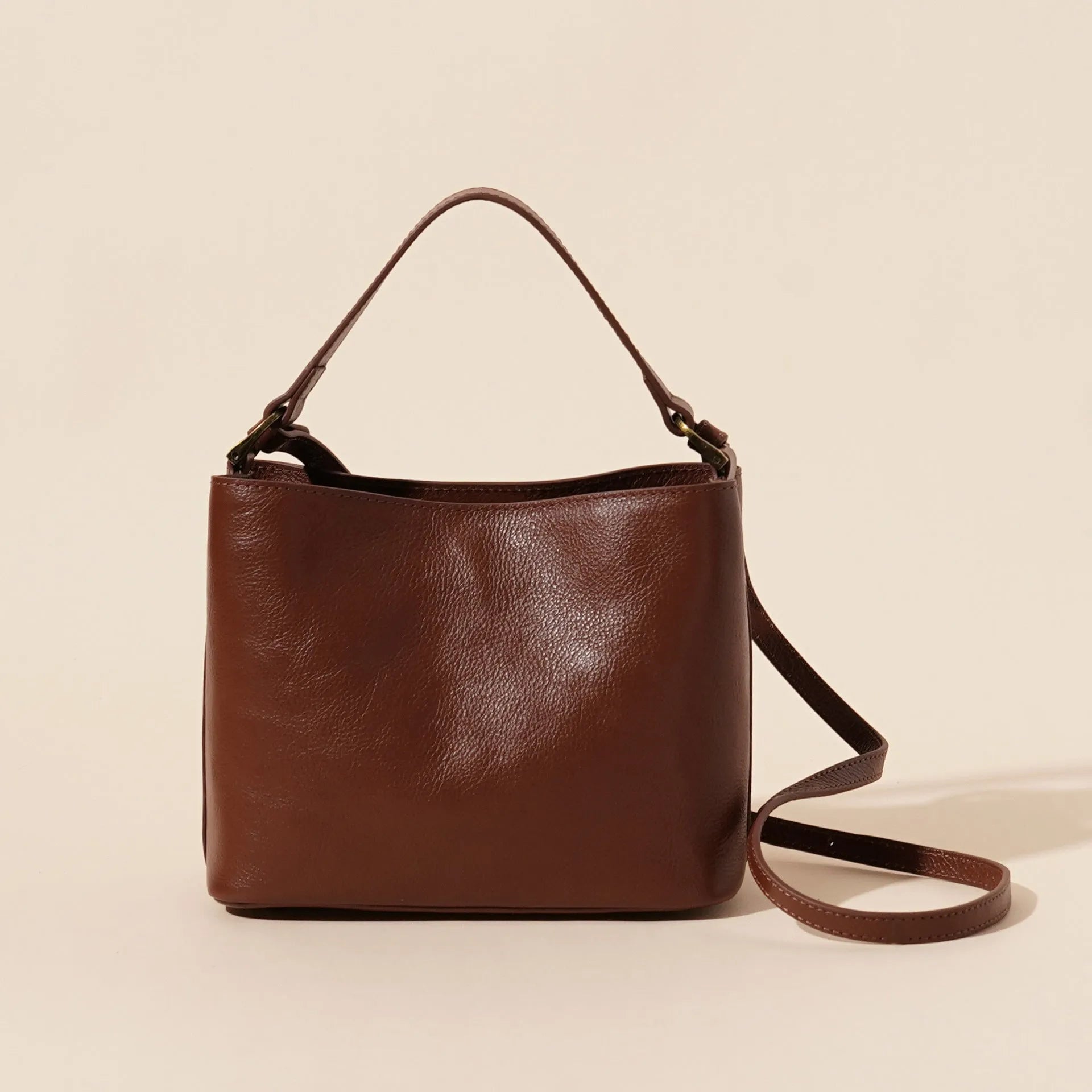 Sugar brown genuine leather women's shoulder handbag with sewing thread detailing on a white background