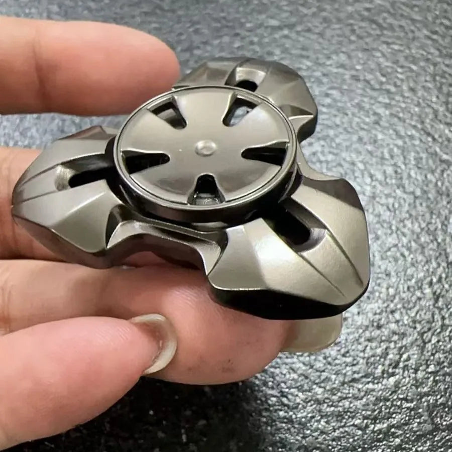 Alloy decompression fingertip gyro toy in gun colour finish on a dark background