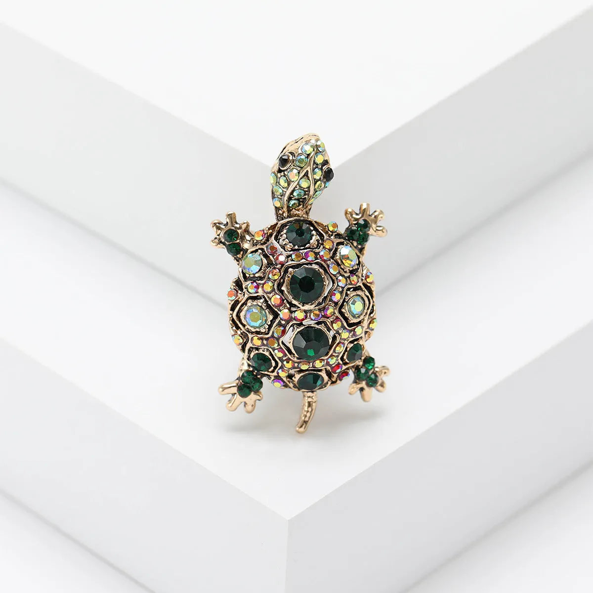 Fashion retro rhinestone turtle brooch in green on a textured surface