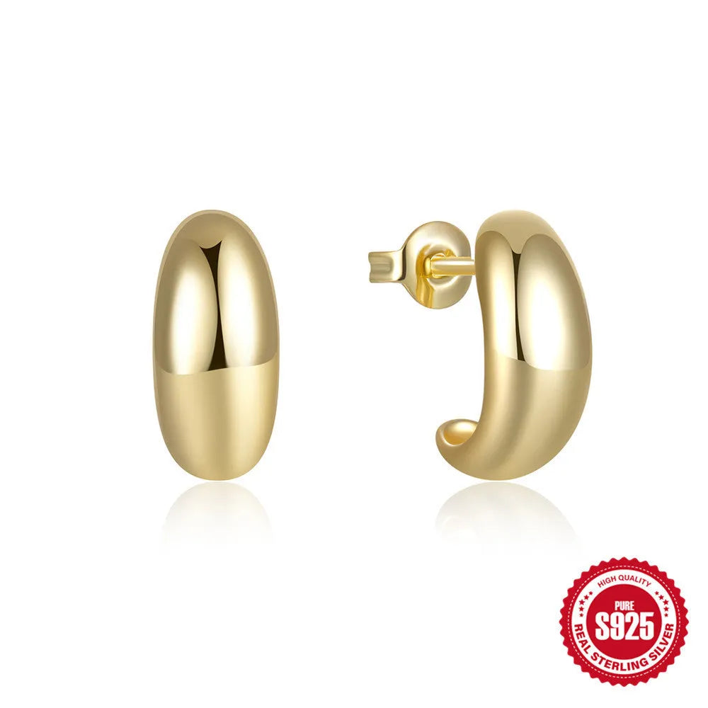Glossy gold and silver tone C-shaped sterling silver stud earrings on a plain background.