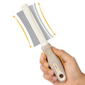 White double-sided pet grooming brush showing comb and deshedding sides, with ergonomic anti-slip handle.
