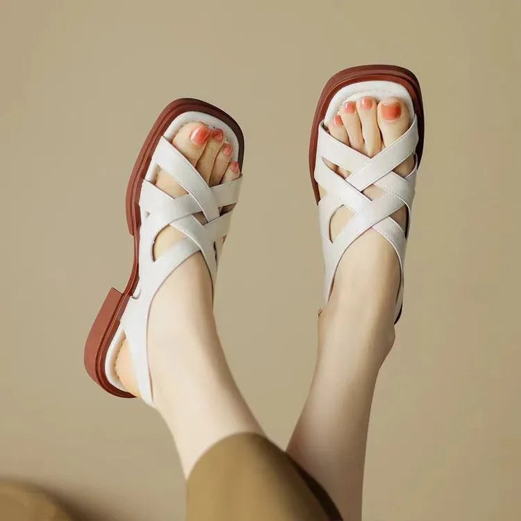 Glossy black patent leather women's sandals with square toe and winding tape closure on a rubber sole.