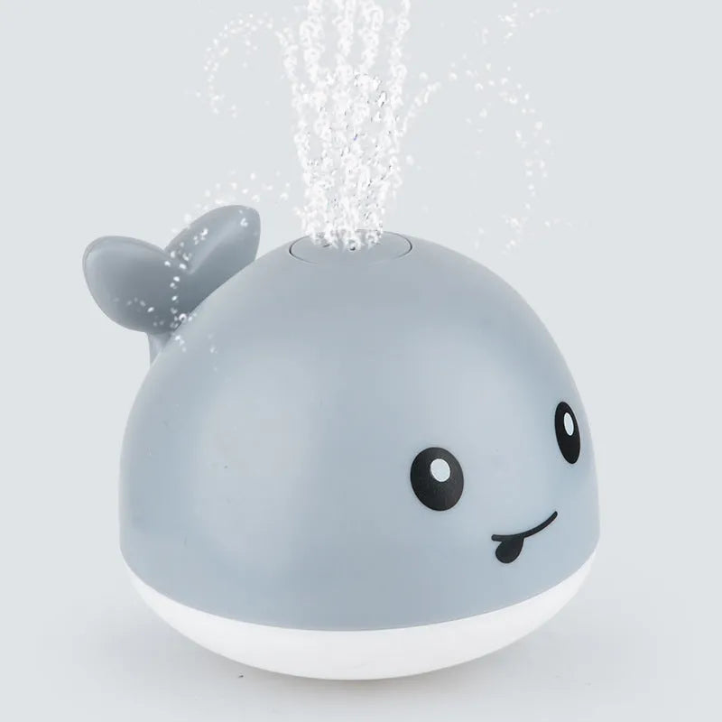 White and blue electric whale bath toy spraying water with lights on a base.