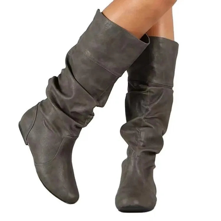Women's black slip-on flat ankle boots with round toe and high shaft on a neutral background.