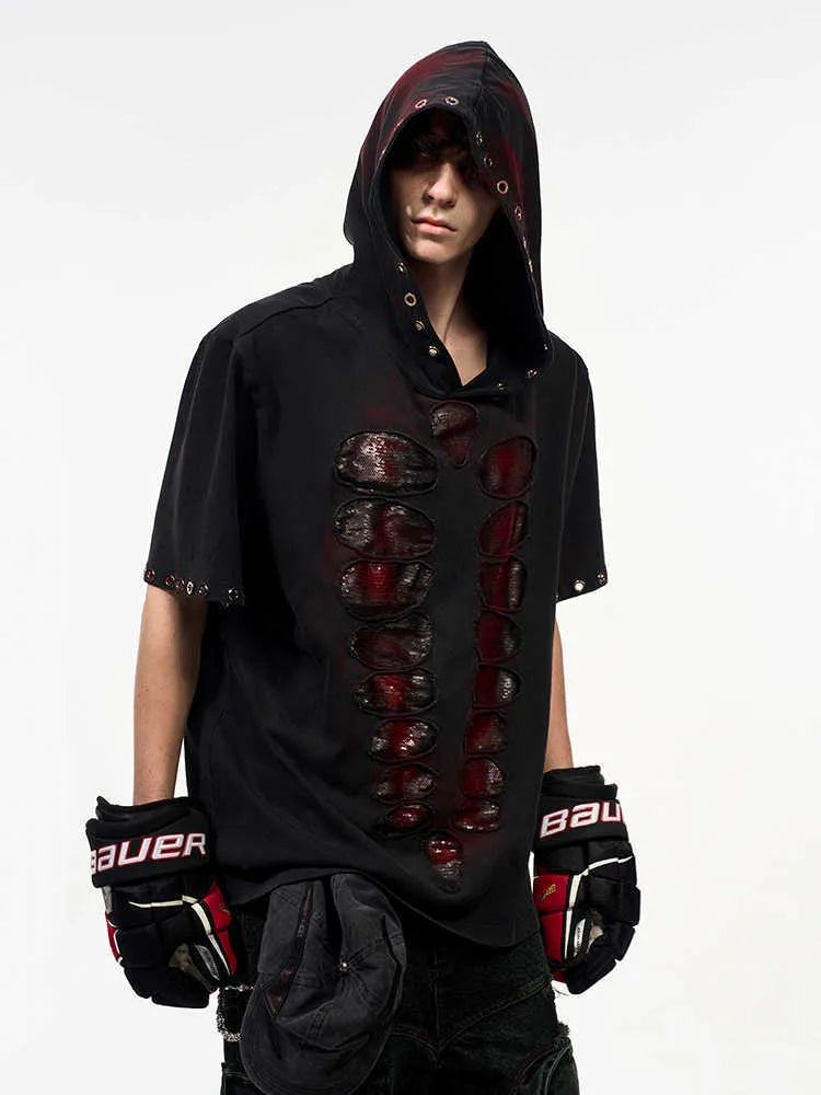 Black loose-fit men's hooded T-shirt covered in reflective sequins, shown in a casual setting.