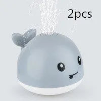 White and blue electric whale bath toy spraying water with lights on a base.