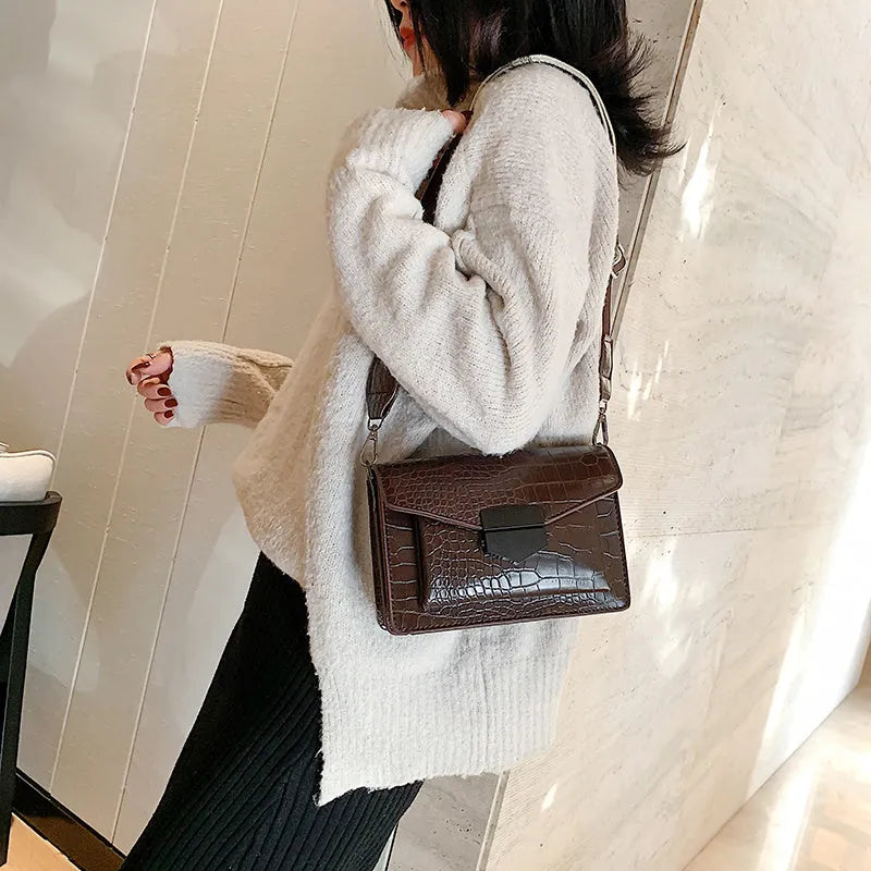 Vintage-style women's crossbody bag in PU leather, shown in black, with adjustable strap.