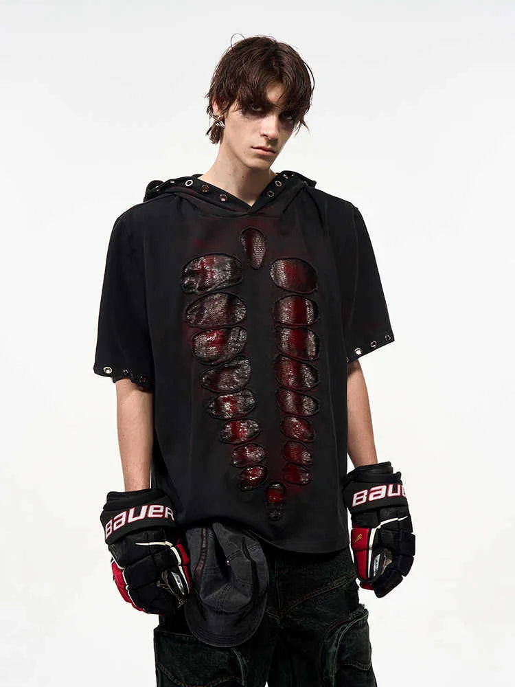 Black loose-fit men's hooded T-shirt covered in reflective sequins, shown in a casual setting.