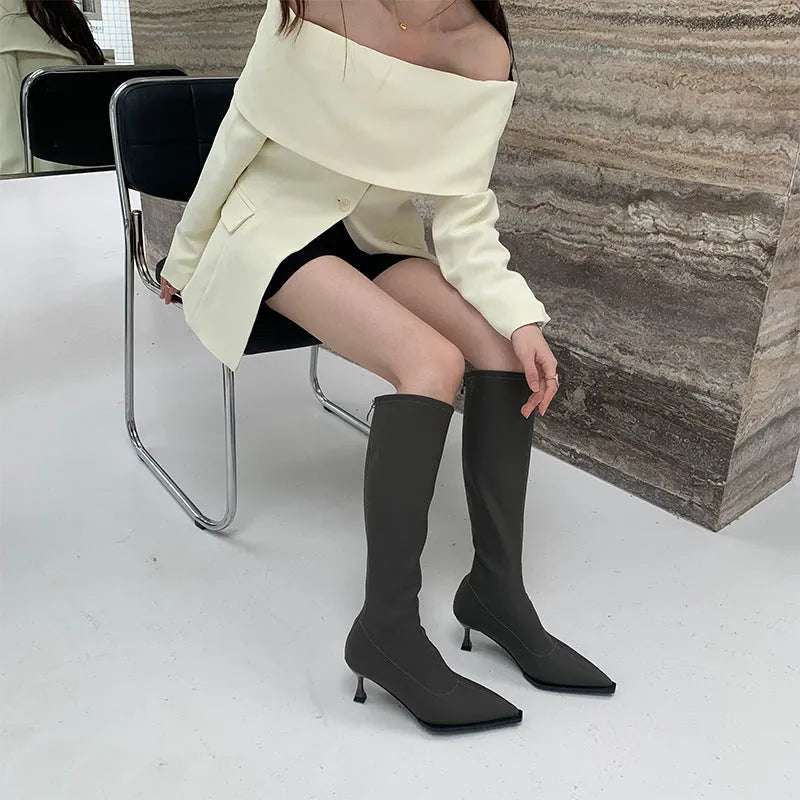 Black pointed toe women's below-the-knee stiletto boots with a back zipper on a white background