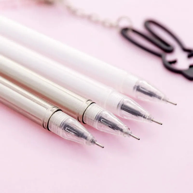 White gel pen with paper crane pendant and black gel pen with rabbit pendant on cap.
