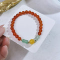 Handmade red agate bracelet with dragon motif and lucky charm beads.