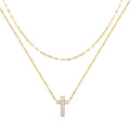 Close-up of a sterling silver double-layer cross pendant necklace with twin diamond accents on a clavicle chain.