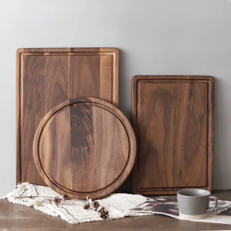 Black walnut wood double-sided cutting board with juice groove and side handle on kitchen counter