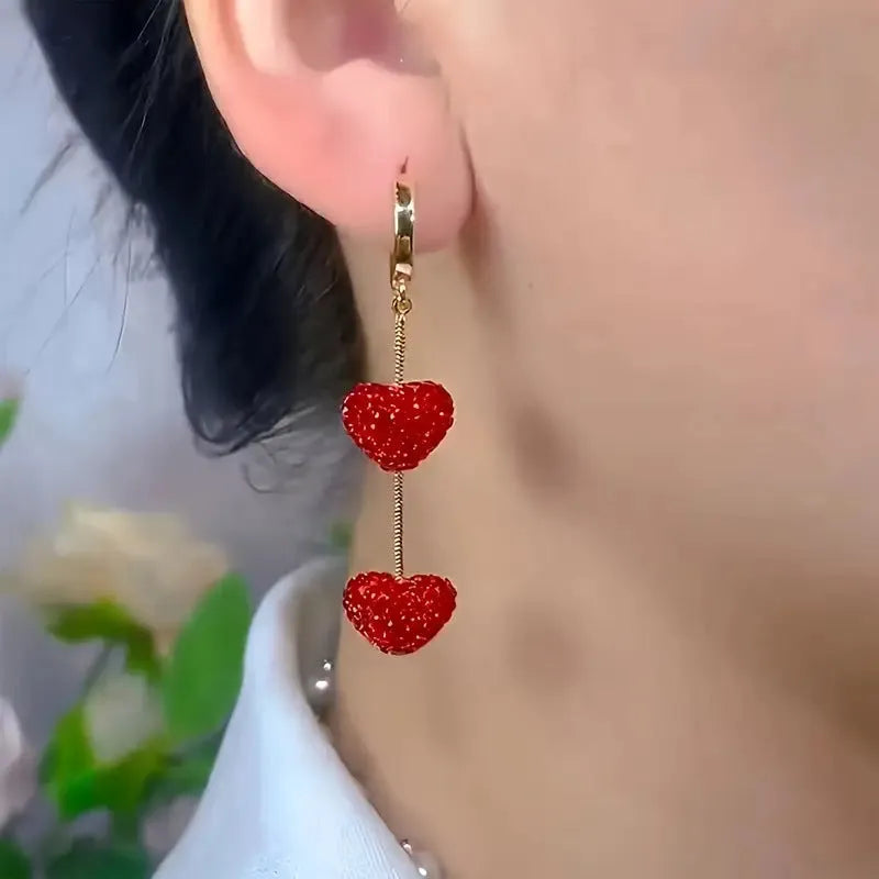 Red heart-shaped long earrings for women made of alloy with an electroplated finish, shown against a neutral background.